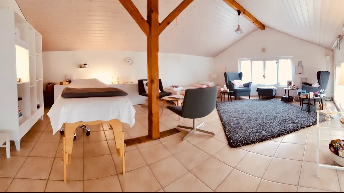 Vue d'ensemble du cabinet : table de relaxation, poutres en bois, coin fauteuils